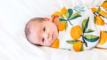 Newborn baby swaddled in colorful blanket.