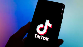 A hand holding a cellphone with the Tiktok logo on its screen.