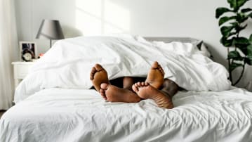 Couple in bed with feet sticking out from underneath duvet