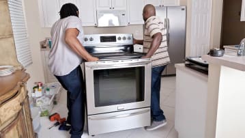 Two men installing a stove in a kitchen