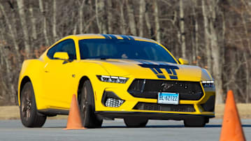 Ford Mustang GT being tested at Consumer Reports' Auto Test Center, driven around orange cones with trees in background