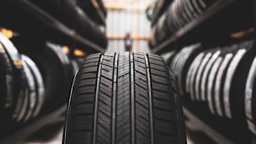 A tire up close in the middle of an aisle full of tires on both sides.