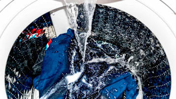 the inside of a washing machine with clothes in it and water dispensing