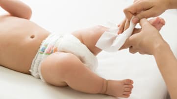 caregiver wiping a baby's leg with a baby wipe
