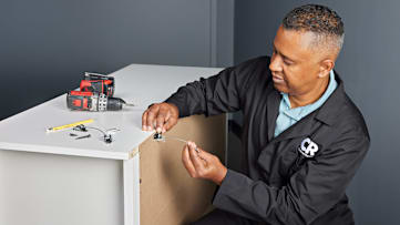 Consumer Reports Project Test Leader Jose Amezquita attaching wall anchor kits to a dresser