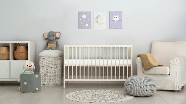 Baby nursery with crib, art on the wall, and chair.