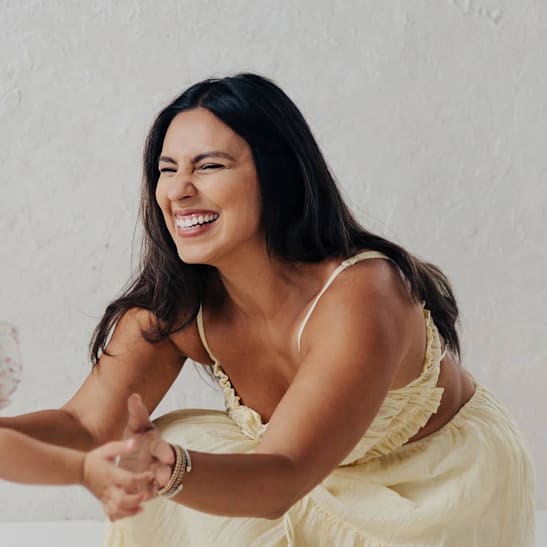 Woman in yellow dress squinting and smiling