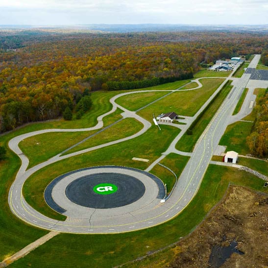Aerial view of the CR test track in Connecticut, showing the track loop and the CR logo in the middle of a roundabout.