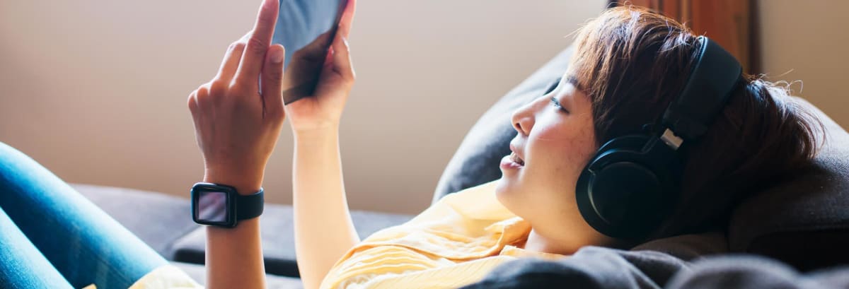 Woman watching tablet with wireless headphones