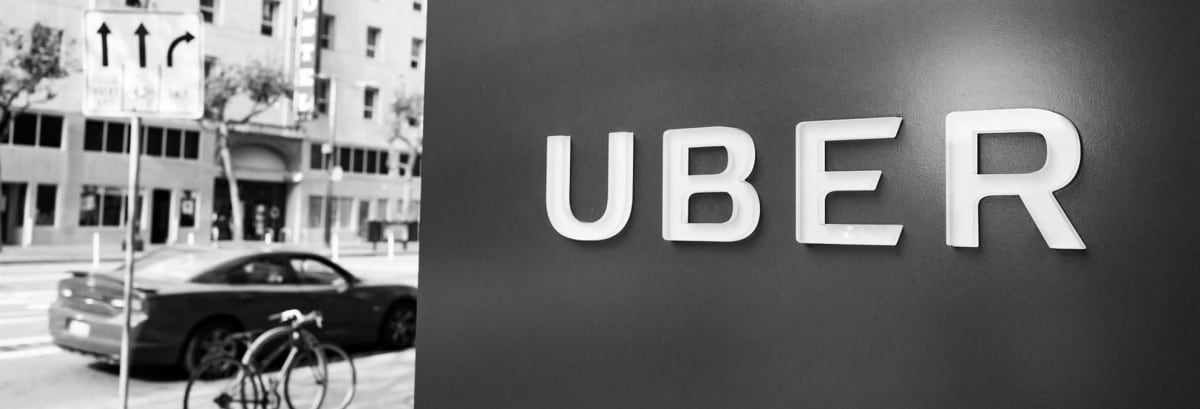 Sign with logo at the headquarters of car-sharing technology company Uber in the South of Market (SoMa) neighborhood of San Francisco, California, with red vehicle visible in the background parked on Market Street, October 13, 2017. SoMa is known for having one of the highest concentrations of technology companies and startups of any region worldwide. (Photo by Smith Collection/Gado/Getty Images)