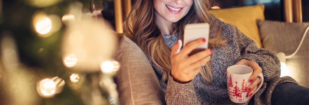 Woman on smart phone in front of christmas tree