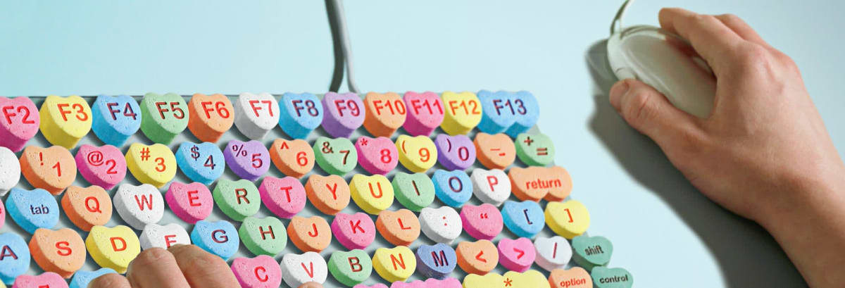 Man typing on computer keyboard made of candy hearts