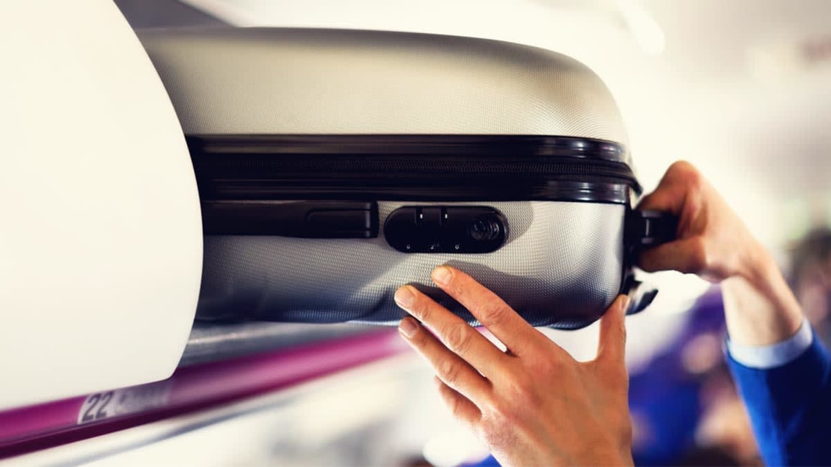Carry on luggage being stowed in overhead compartment