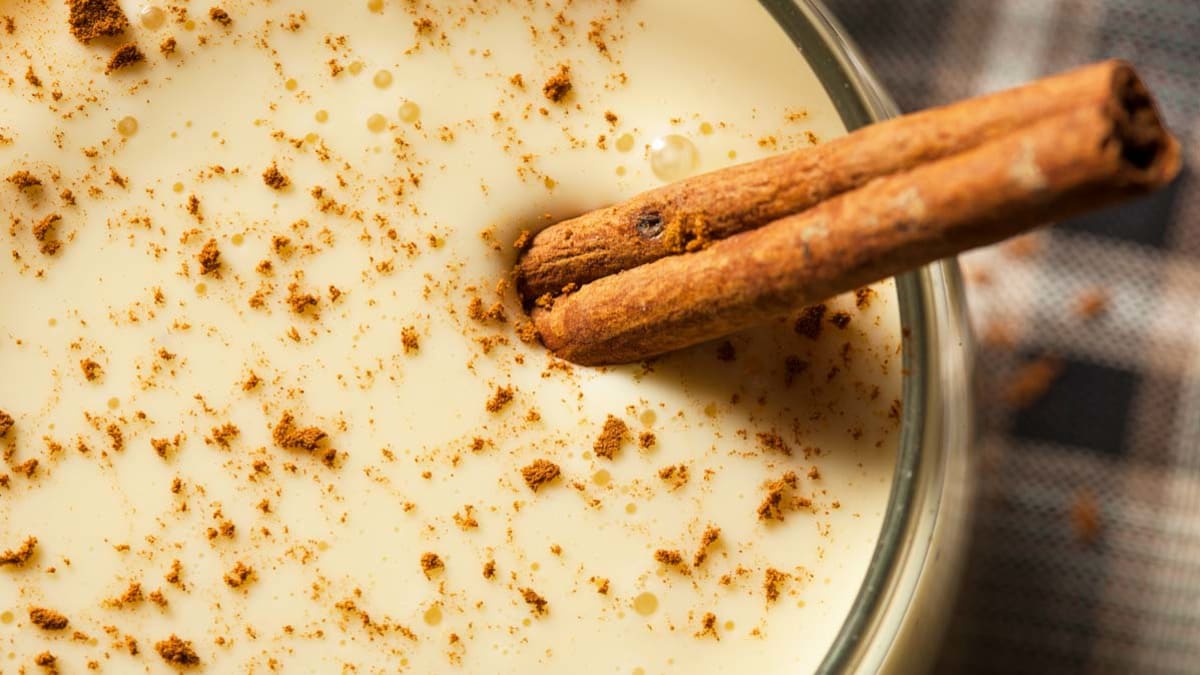 eggnog in glass with cinnamon stick garnish
