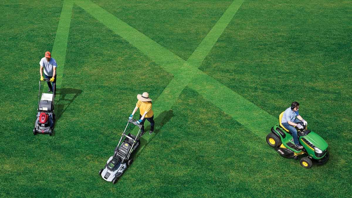 Three people pushing three different types of mowers on a lawn.