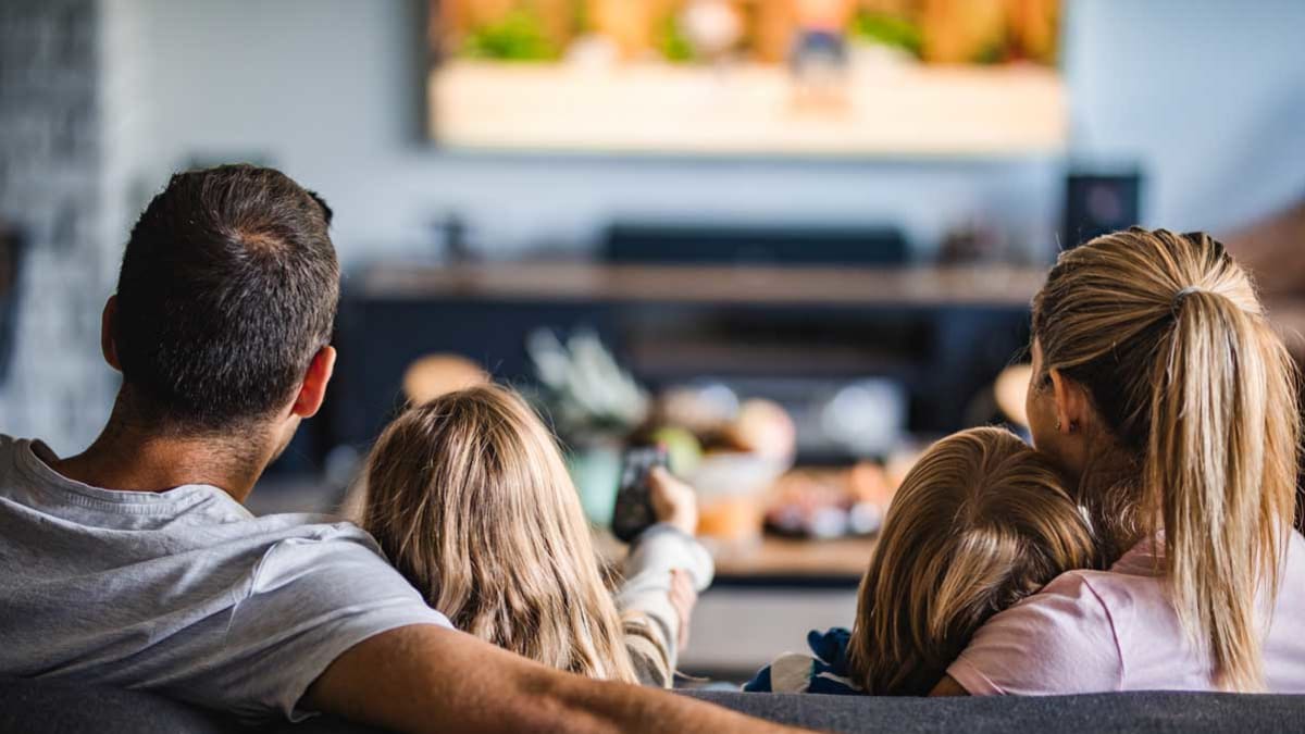 family sitting watching tv, child holding remote