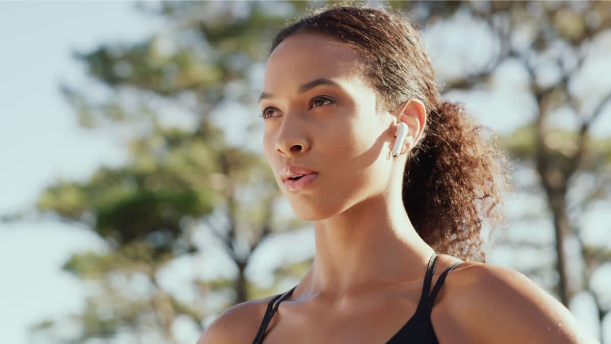 Person wearing earbuds while outside exercising.