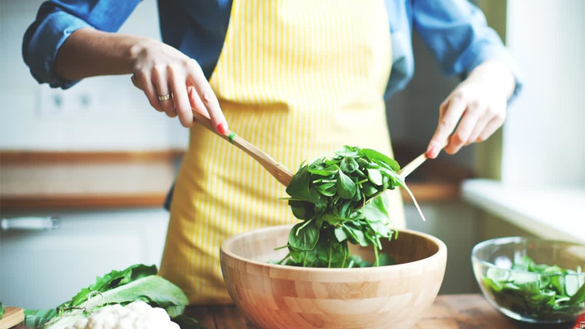 person making a salad spinach  and other vegetables in a kitchen