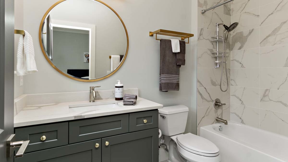 small bathroom with under the sink cabinet and large round mirror above sink