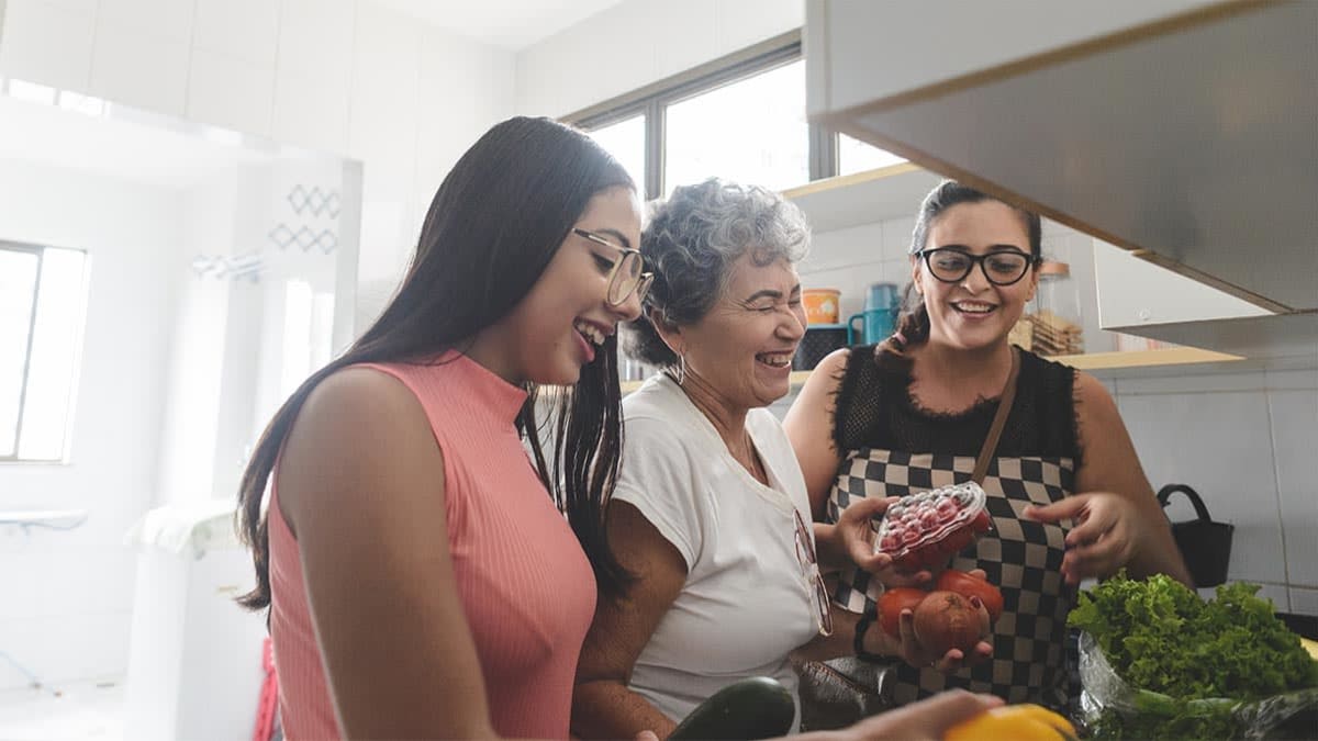 Three members of a family without a face mask on standing together in a kitchen