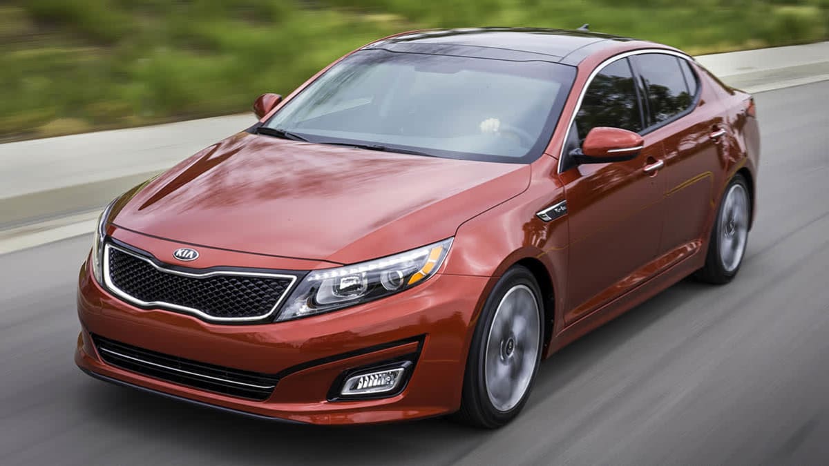 A red 2014 Kia Optima driving down a road