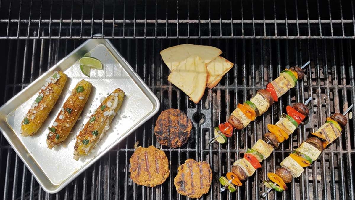 A variety of plant-based foods being cooked on a gas grill