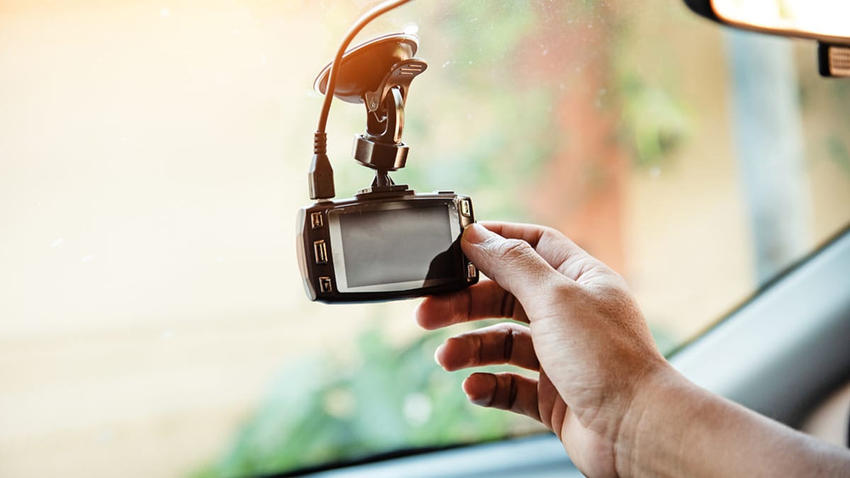 Person adjusting dash cam on their car's windshield.