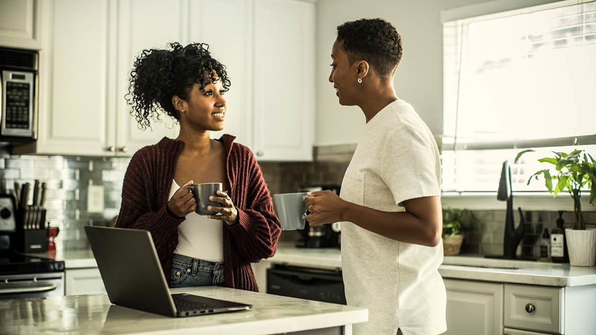 A Black couple speaking in their kitchen.