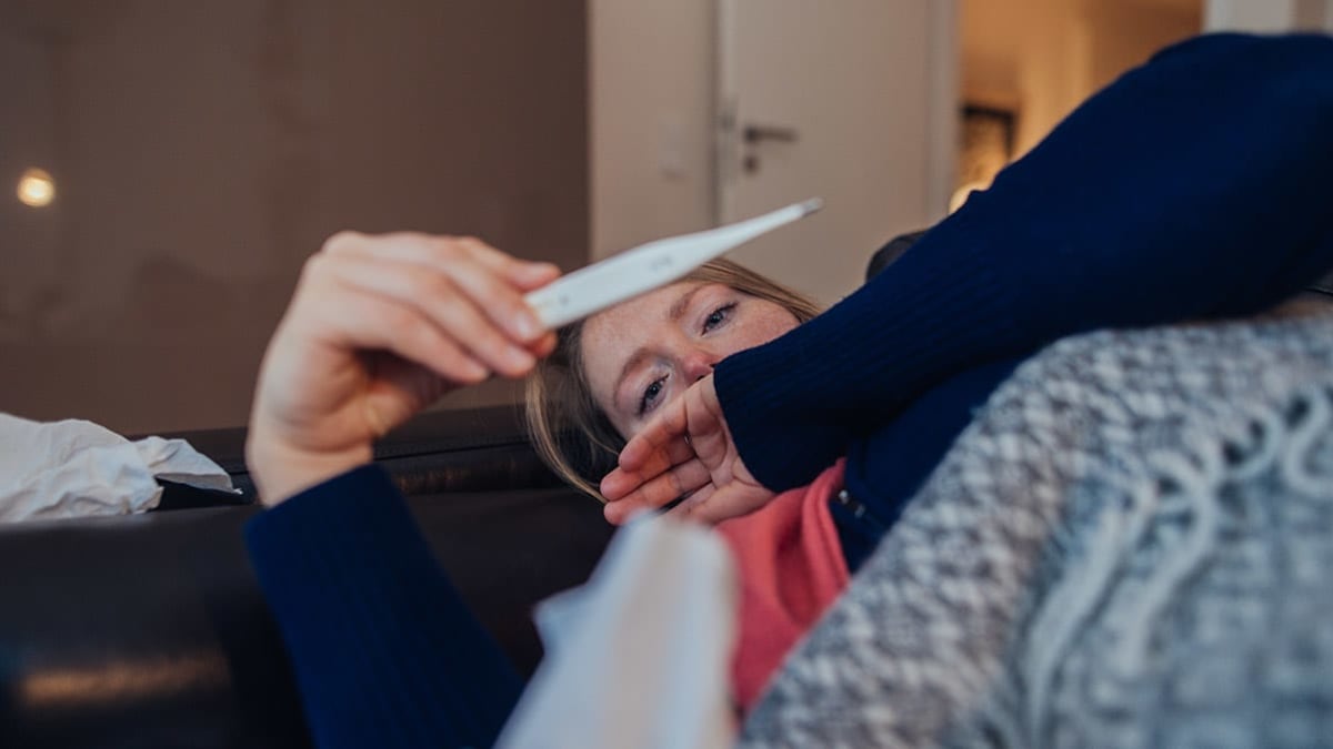 Person laying down looking at a thermometer reading.