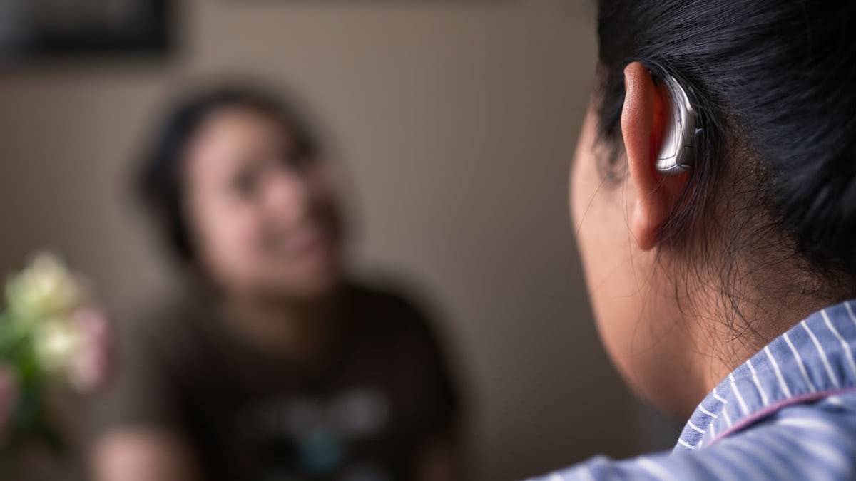 Person wearing a hearing aid in conversation with someone else.