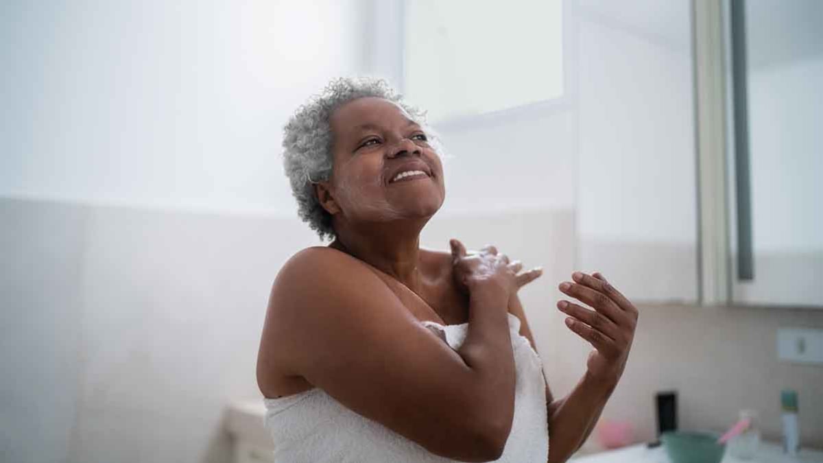 person in towel putting on lotion