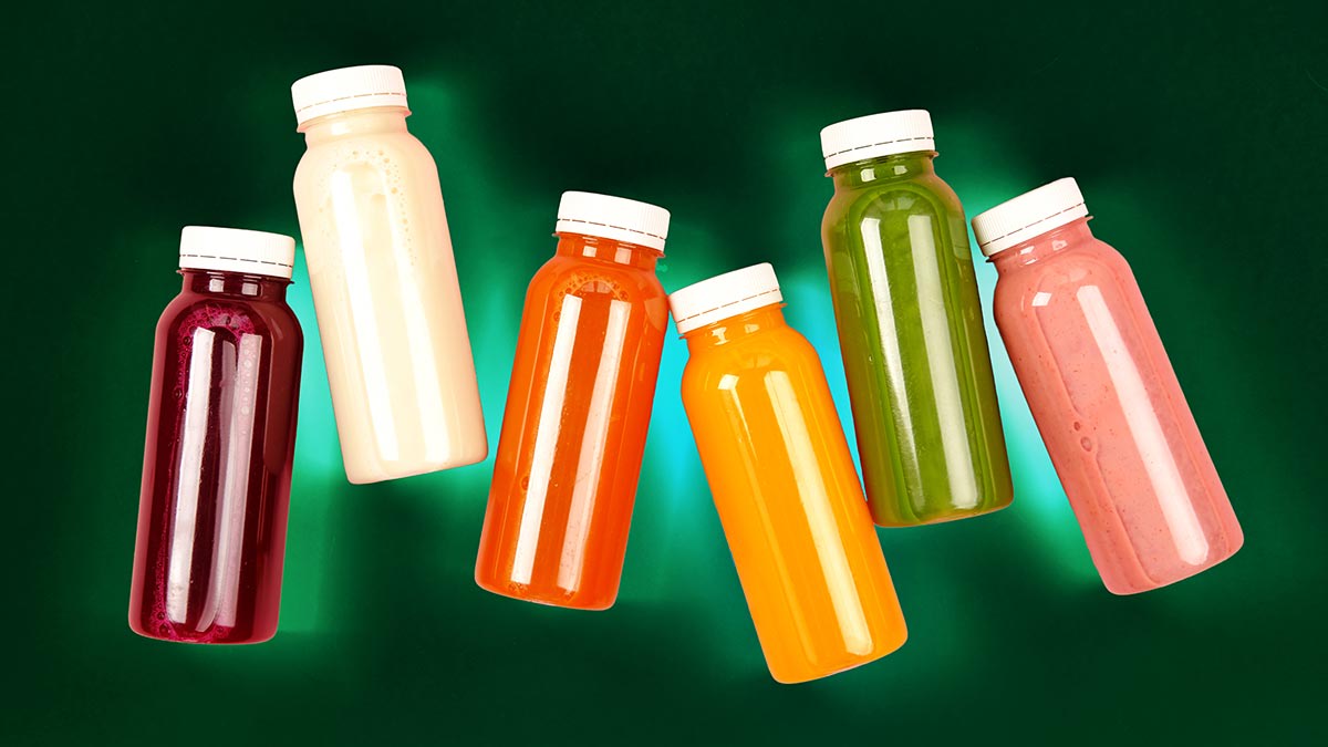 six different colors of juices in bottles laying flat
