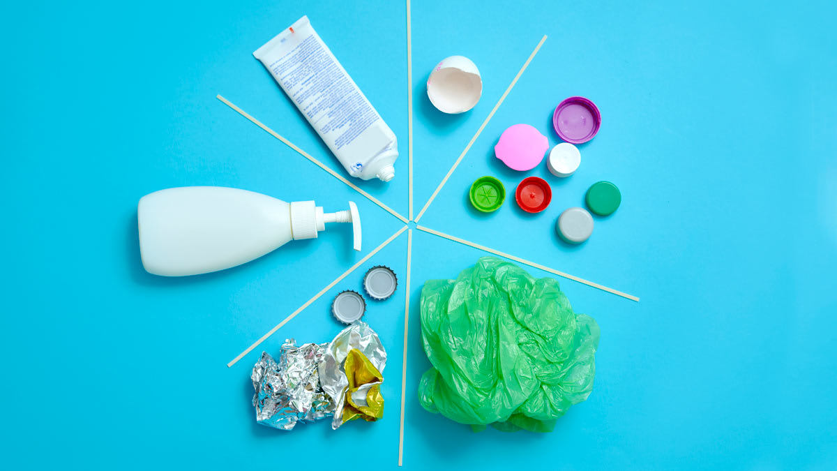 Top shot of circular diagram made out of different kinds of garbage separated for recycling from each other on blue background.