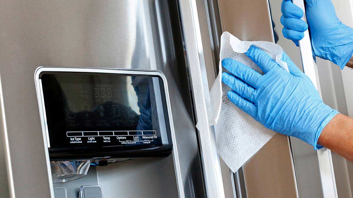 Person wiping refrigerator with gloves on