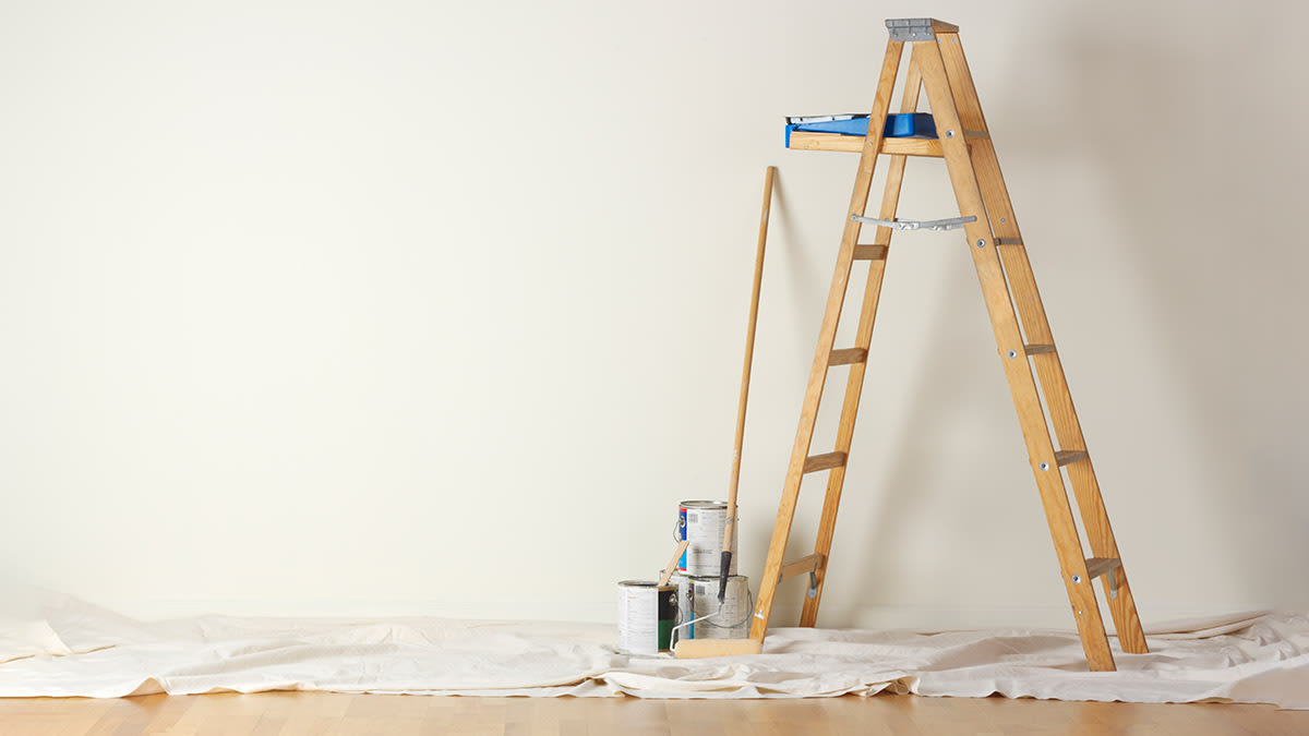 A room with a ladder and painting supplies.