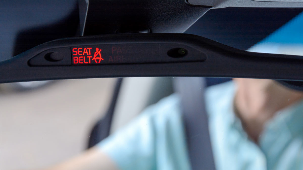 A Seat Belt reminder on a rearview mirror with a driver