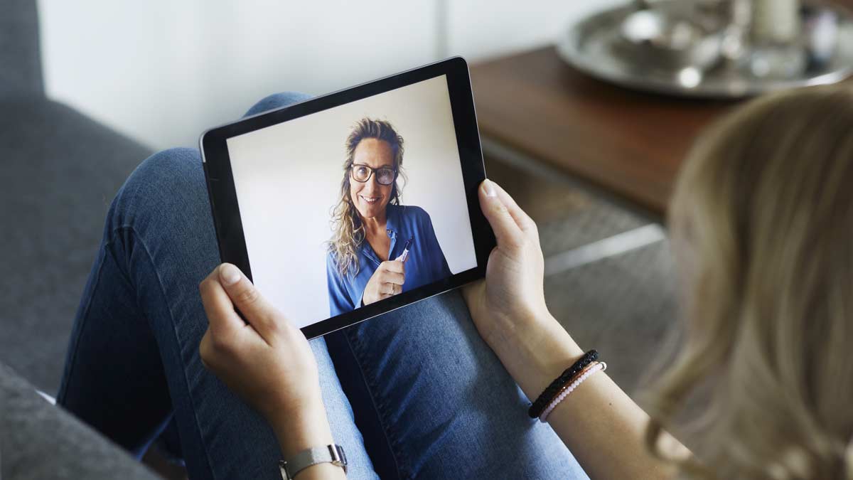 person sitting on couch holding iPad while having a video therapy call