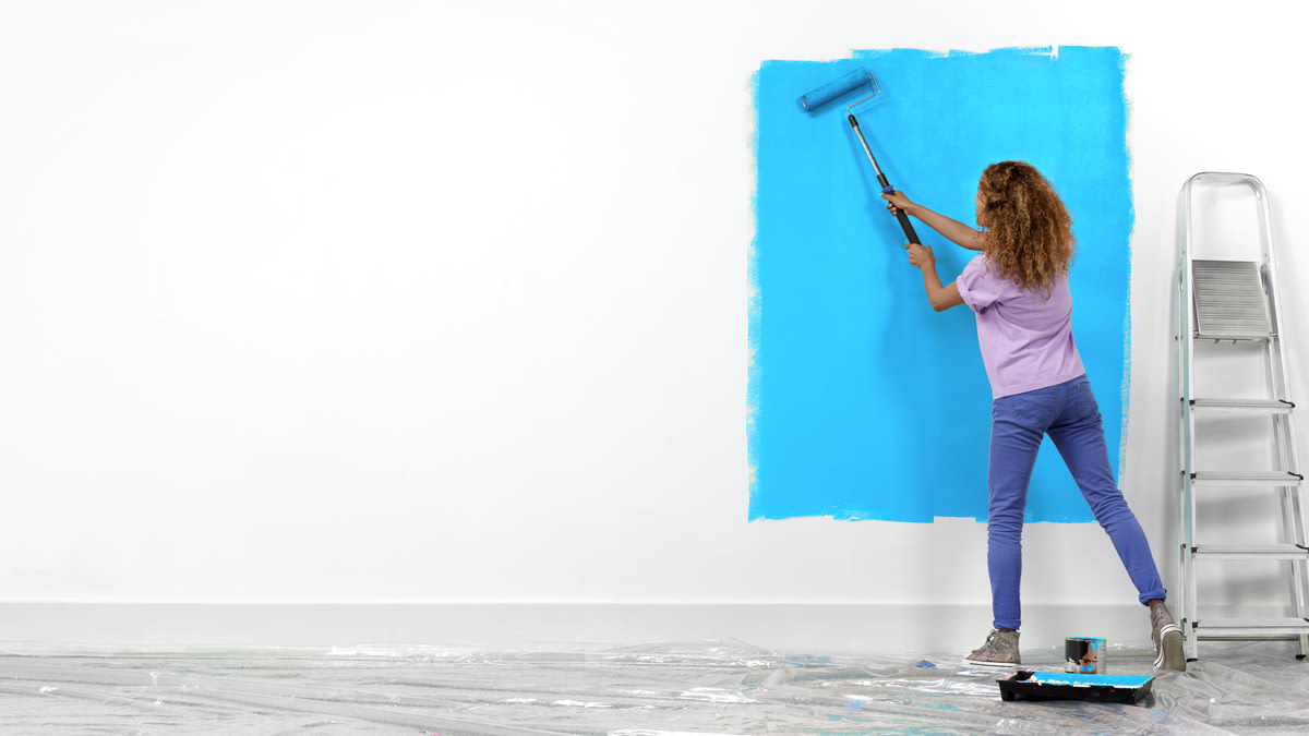 Woman painting a wall blue