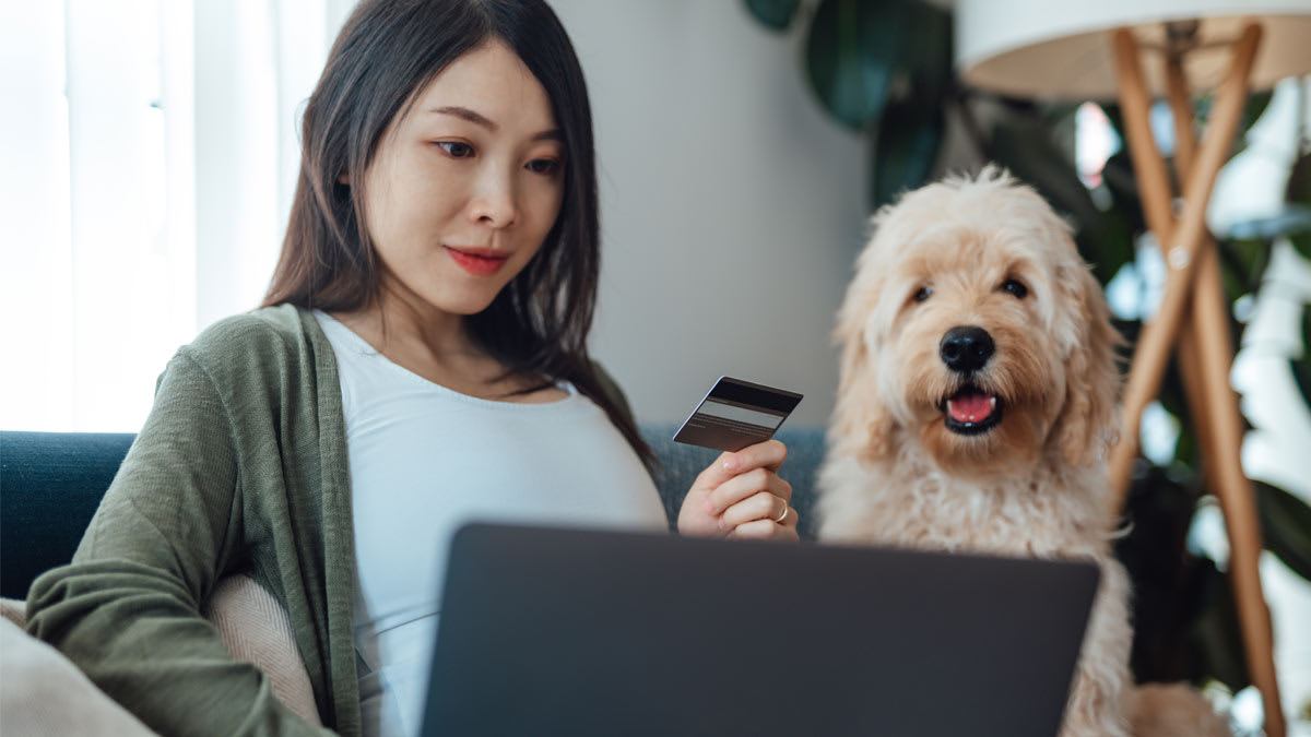 Woman buying items online with dog watching by her side