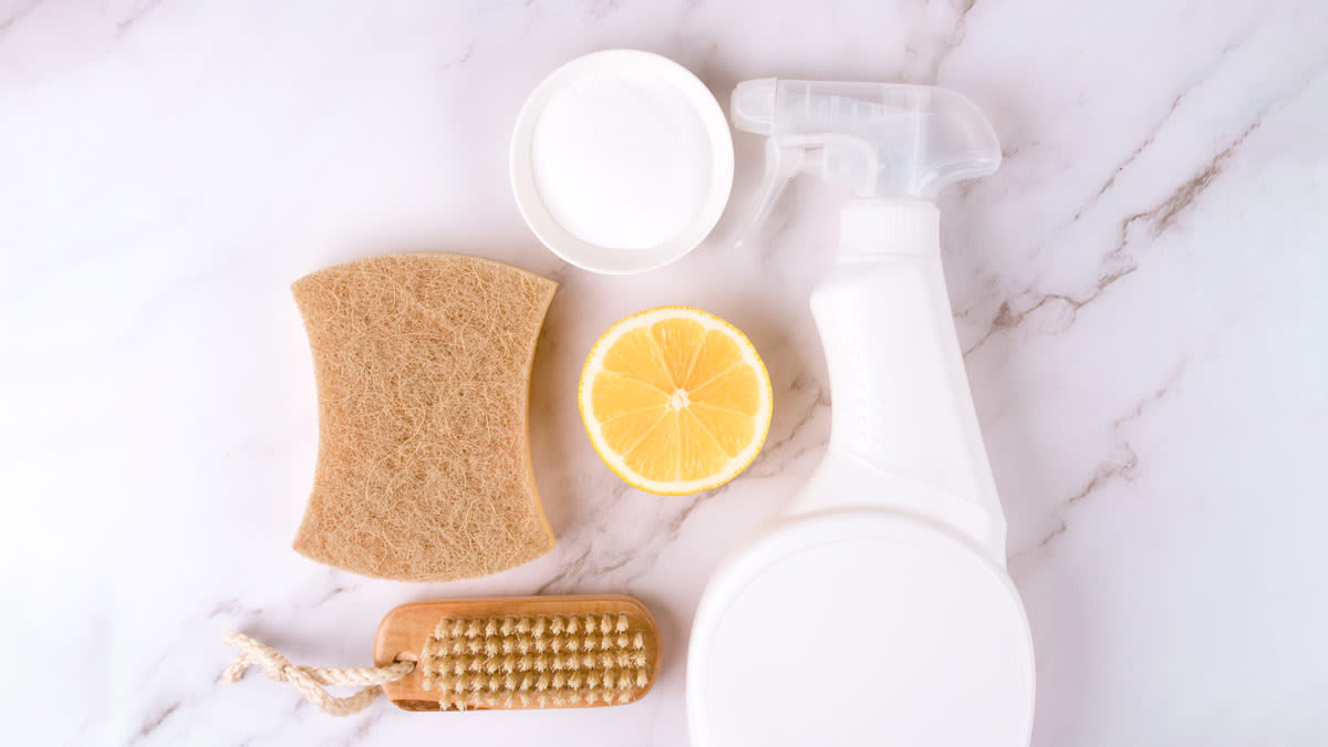 Set of natural household cleaners made of simple eco ingredients, bamboo brush, organic dishcloth, lemon, baking soda, citric acid on marble background