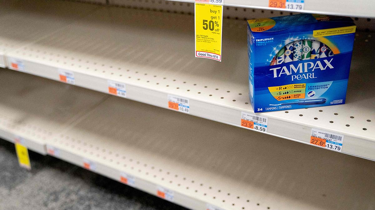 A sole box of Tampax tampons sits on otherwise empty shelving at a store.
