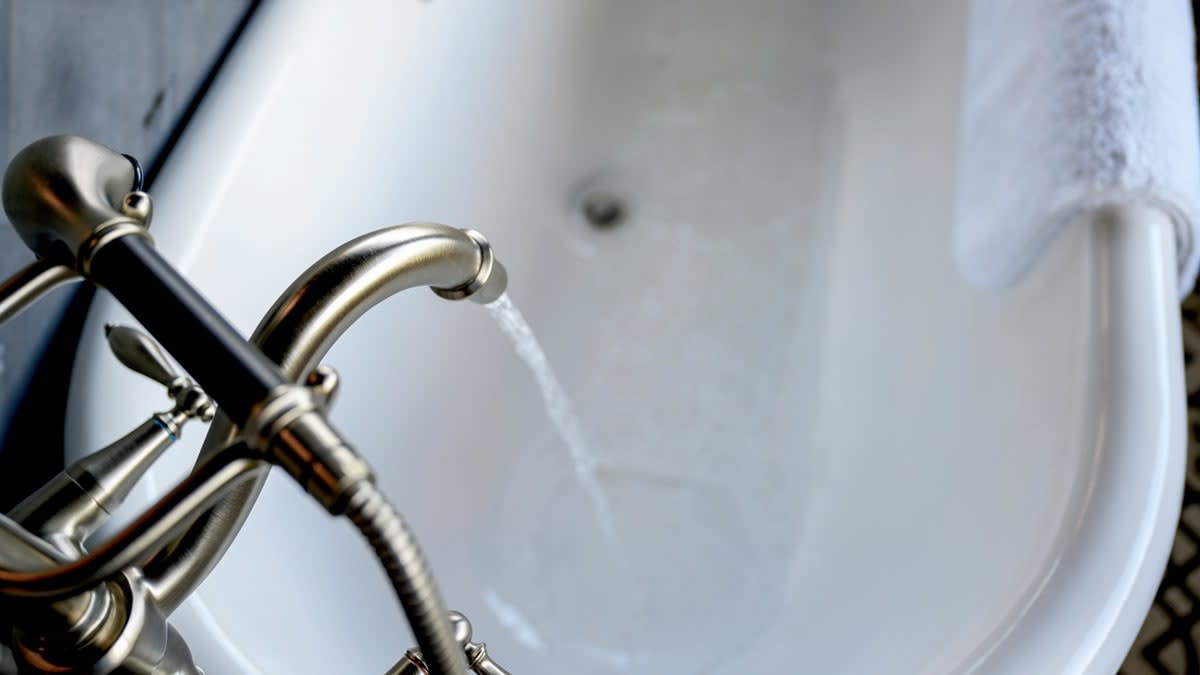 overhead view of water filling white ceramic bathtub