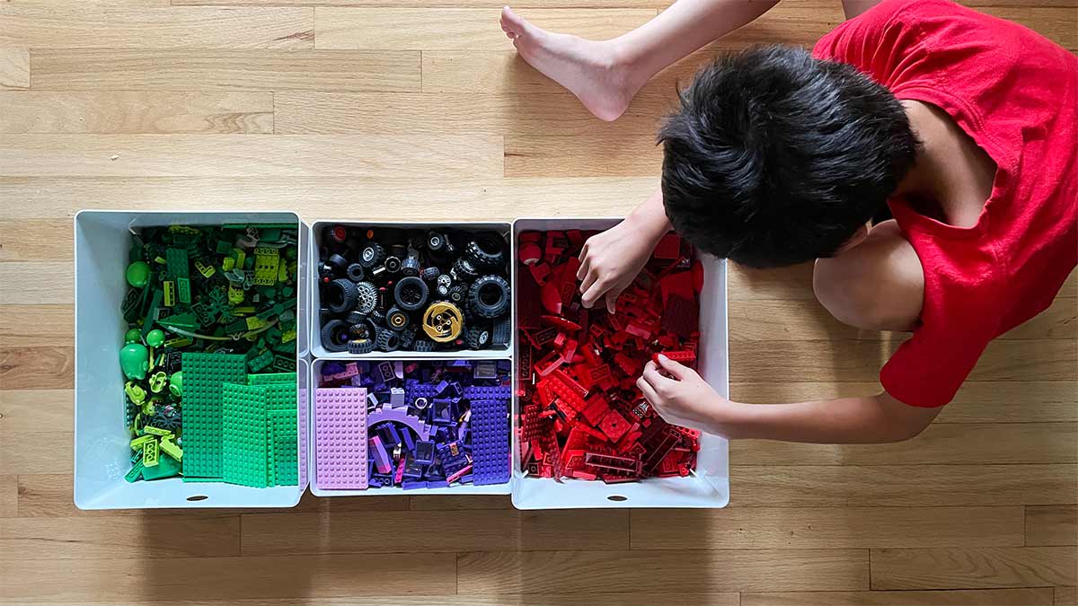 Oliver looking through his color-coordinated bins of Legos.