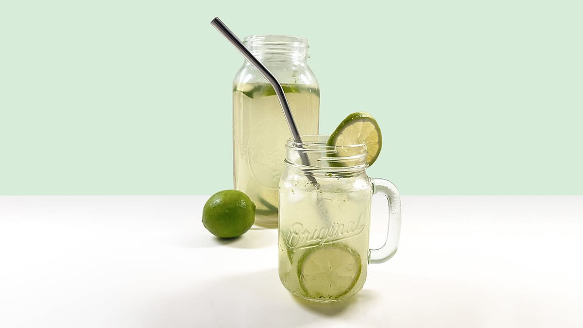 A container and glass of homemade lime agua fresca