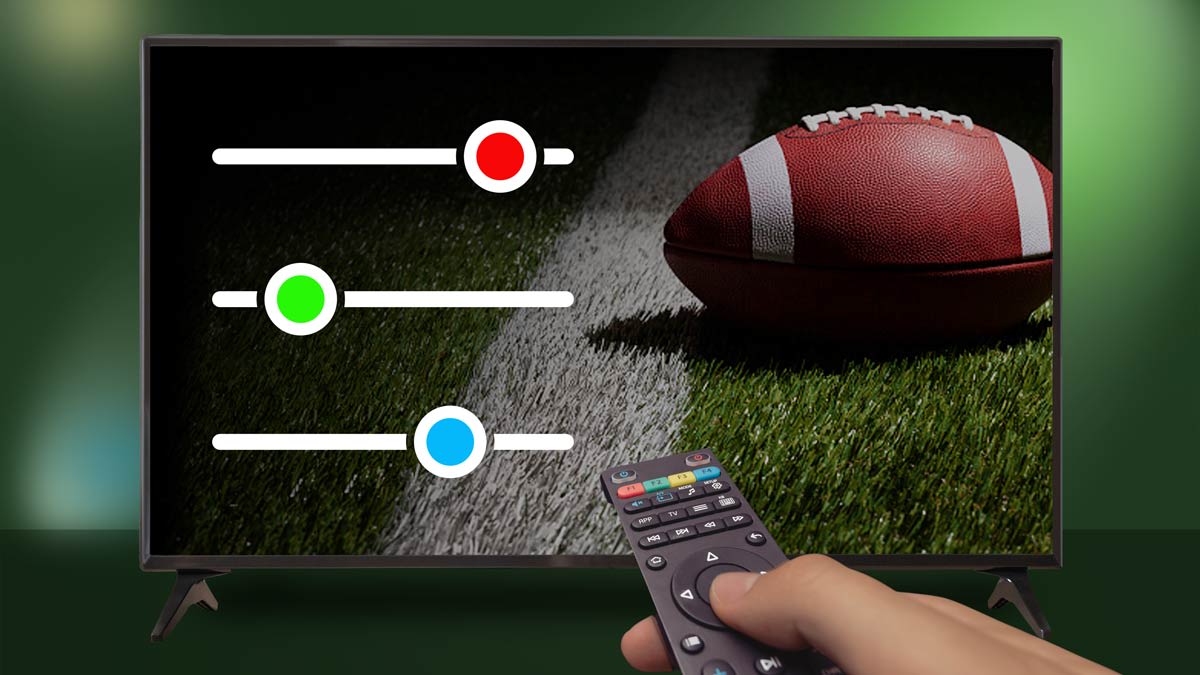 Hand holding TV remote adjusting color balance on TV with football on the screen.