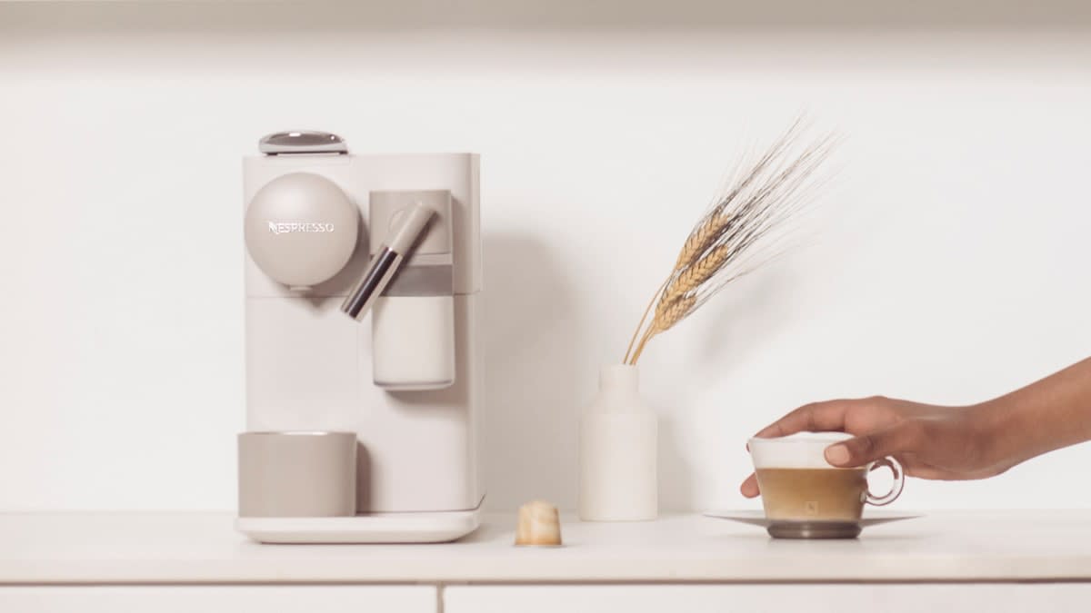 Nespresso by DeLonghi Lattissima One Espresso Maker EN500BW/W with hand reaching for cup of coffee