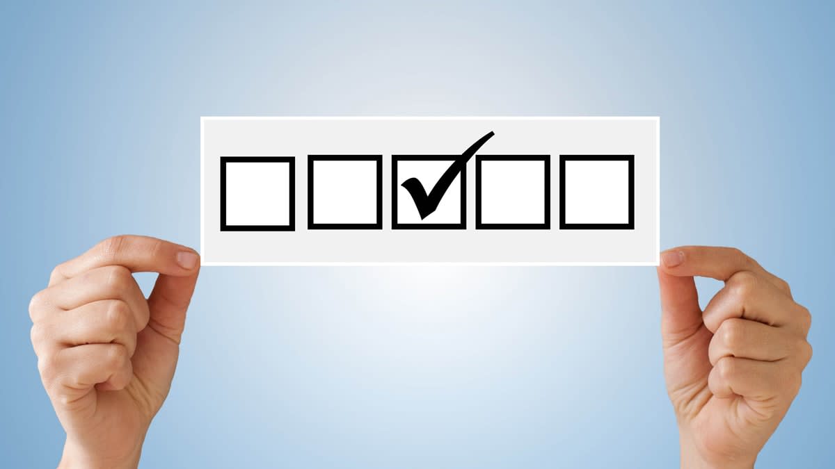 hands holding illustration of 5 boxes with the middle one checked off