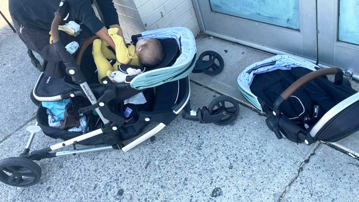 A baby laying in a broken and collapsed Mockingbird Single to Double stroller on the sidewalk.