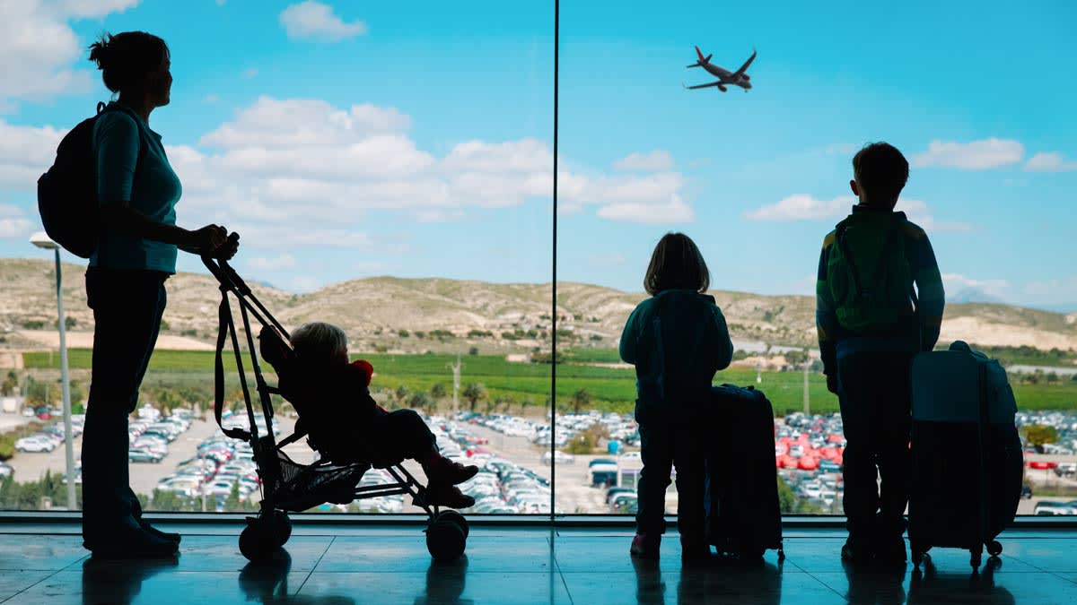 Mother with child in stroller and two other children at the airport.