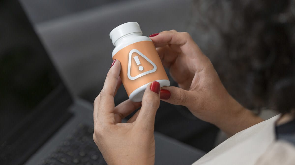 Woman looking at bottle of supplements with warning label.